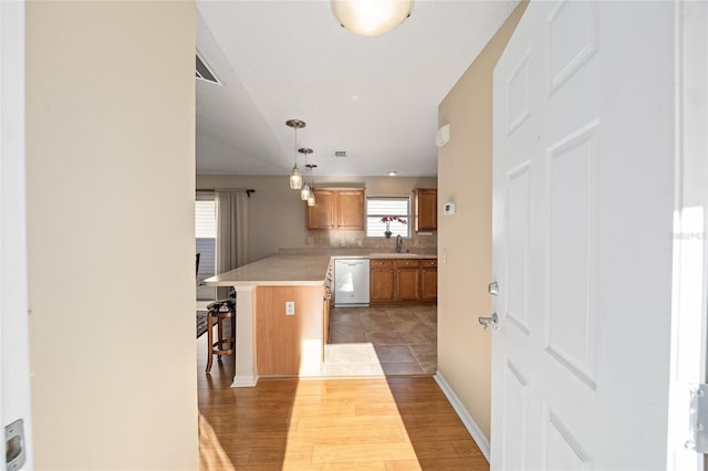 kitchen featuring sink, a kitchen bar, white dishwasher, hanging light fixtures, and hardwood / wood-style floors