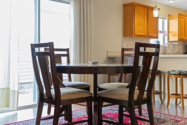 dining area featuring light wood-type flooring, sink, and plenty of natural light