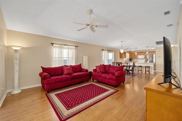 living room featuring ornate columns, plenty of natural light, and light wood-type flooring