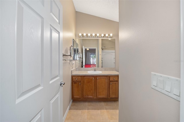 bathroom with vanity, a textured ceiling, tile patterned flooring, and vaulted ceiling