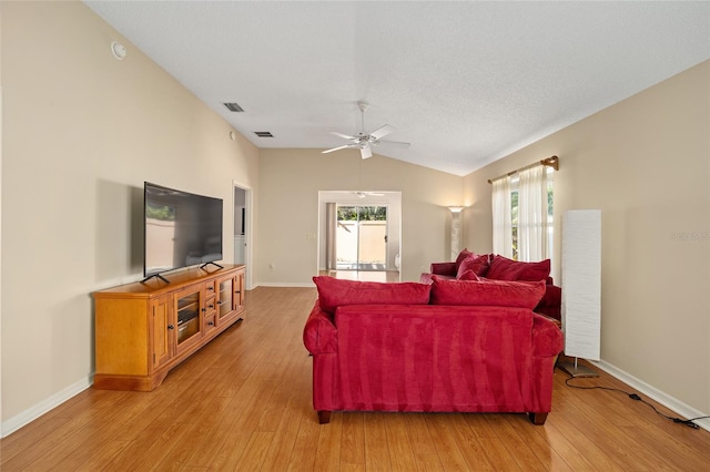 living room with light hardwood / wood-style floors, a textured ceiling, lofted ceiling, and ceiling fan