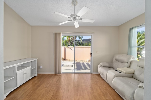 sitting room with a textured ceiling, a healthy amount of sunlight, light wood-type flooring, and ceiling fan