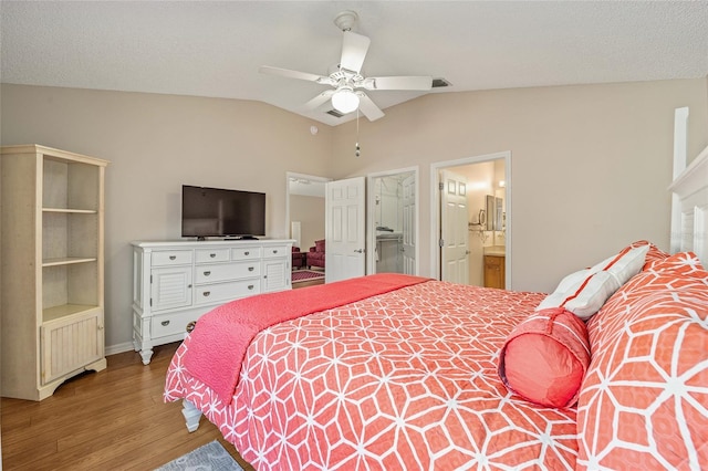 bedroom featuring ensuite bath, ceiling fan, wood-type flooring, a textured ceiling, and vaulted ceiling