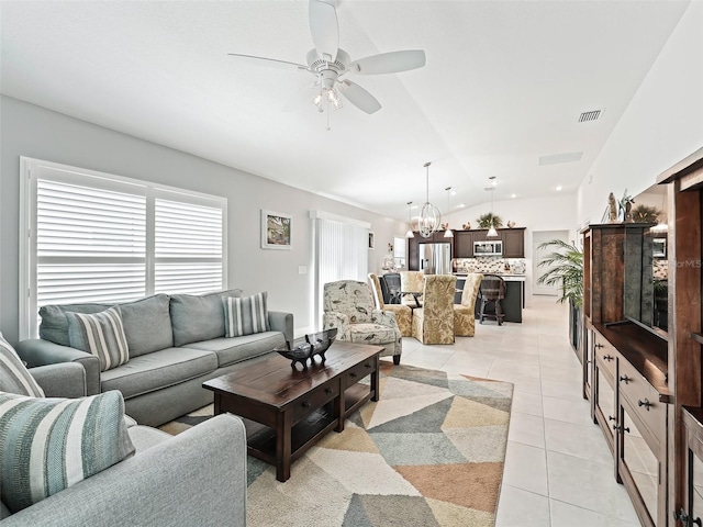 living room with vaulted ceiling, ceiling fan with notable chandelier, and light tile patterned flooring