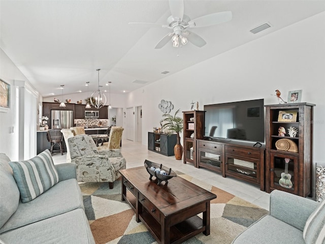 tiled living room featuring ceiling fan with notable chandelier and vaulted ceiling