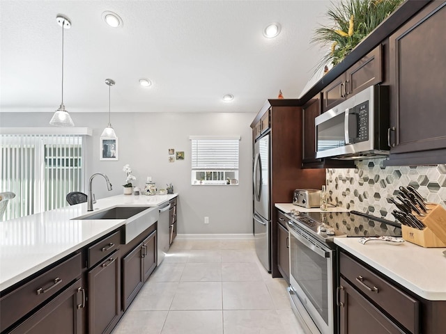 kitchen featuring appliances with stainless steel finishes, sink, dark brown cabinetry, pendant lighting, and decorative backsplash