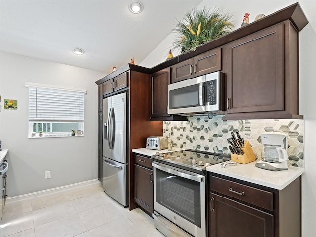 kitchen featuring lofted ceiling, tasteful backsplash, stainless steel appliances, and dark brown cabinets