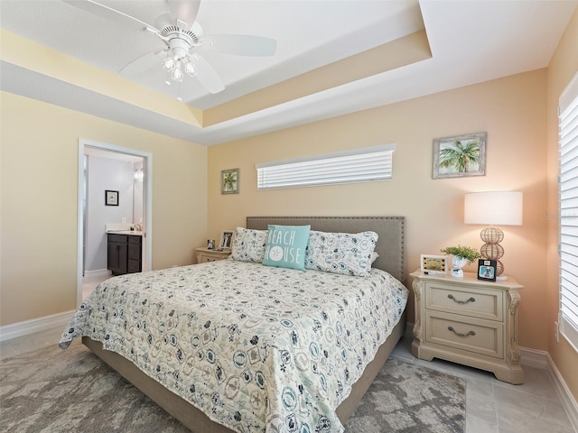 bedroom featuring light carpet, ensuite bath, a raised ceiling, and ceiling fan