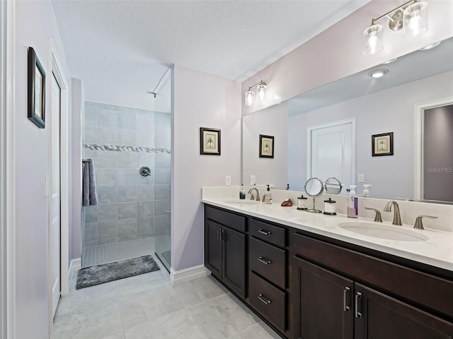 bathroom with a tile shower, tile patterned floors, a textured ceiling, and vanity