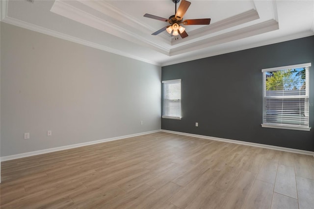 spare room with light hardwood / wood-style floors and a raised ceiling