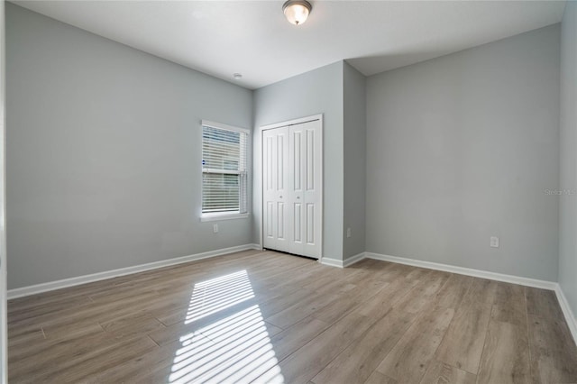 unfurnished bedroom with a closet and light wood-type flooring