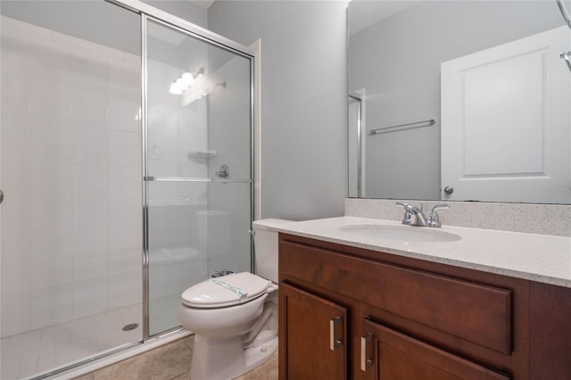 bathroom with a shower with door, vanity, toilet, and tile patterned floors