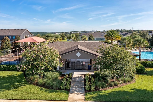 view of front of property featuring a community pool and a front lawn