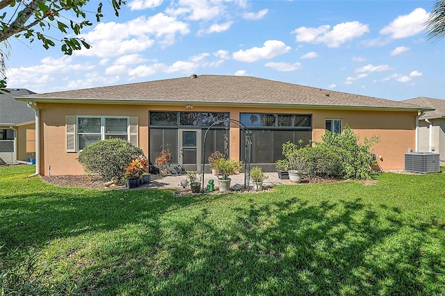 rear view of house with central air condition unit and a lawn