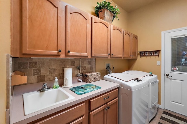 laundry room featuring sink, washing machine and clothes dryer, and cabinets