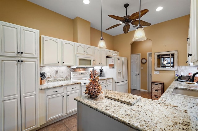 kitchen with white cabinets, light stone counters, and white appliances