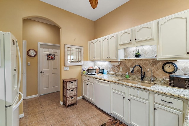 kitchen with decorative backsplash, sink, light tile patterned floors, light stone counters, and white appliances