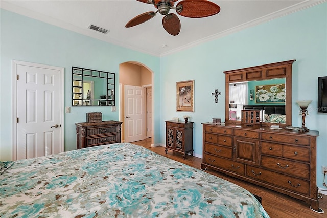 bedroom featuring dark hardwood / wood-style flooring, ornamental molding, and ceiling fan