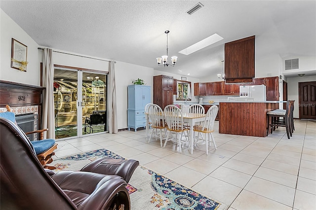 dining room with vaulted ceiling with skylight, a notable chandelier, a textured ceiling, and light tile patterned floors