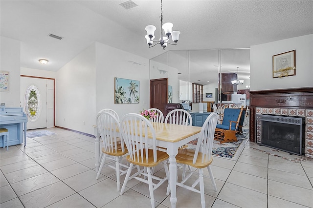 tiled dining space featuring an inviting chandelier, a textured ceiling, and a tiled fireplace