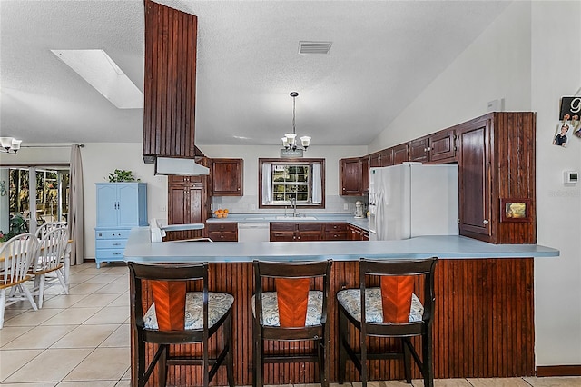 kitchen featuring white appliances, lofted ceiling with skylight, a wealth of natural light, and a chandelier