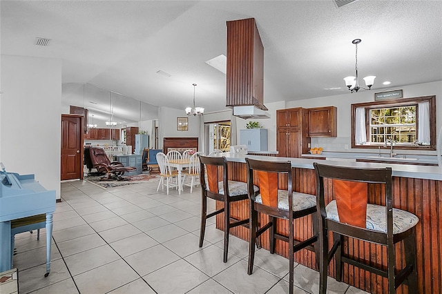 kitchen with sink, a textured ceiling, lofted ceiling, and an inviting chandelier