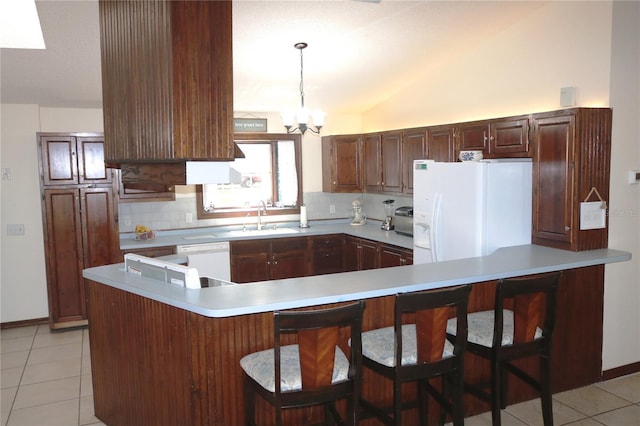 kitchen featuring lofted ceiling, a kitchen breakfast bar, sink, decorative light fixtures, and white appliances