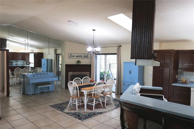 dining space featuring lofted ceiling with skylight, a notable chandelier, a textured ceiling, and light tile patterned floors