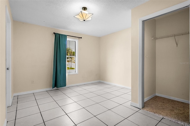 unfurnished bedroom featuring a textured ceiling, a closet, and light tile patterned floors