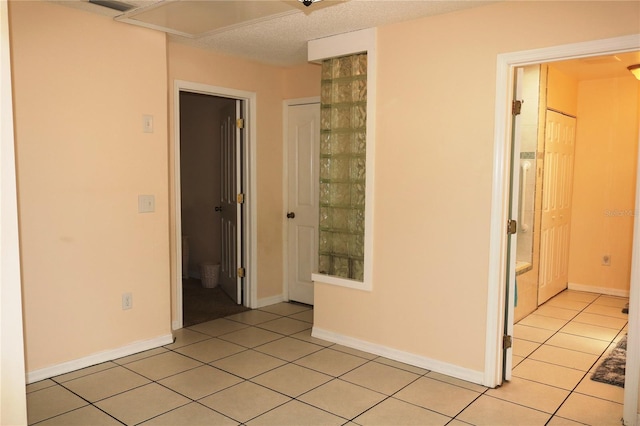 unfurnished room with a textured ceiling and light tile patterned floors