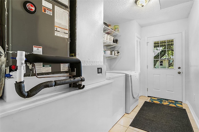 laundry room featuring washer and dryer, a textured ceiling, and light tile patterned floors