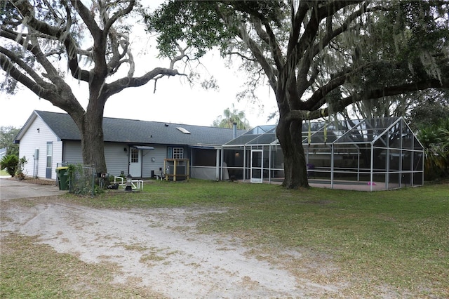 back of house with a lanai and a lawn