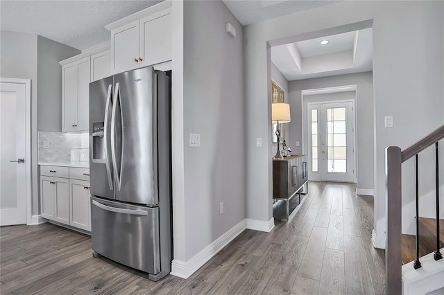 kitchen featuring white cabinetry, stainless steel fridge, a raised ceiling, and dark hardwood / wood-style floors