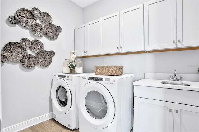 laundry area with sink, washer and dryer, cabinets, and light wood-type flooring