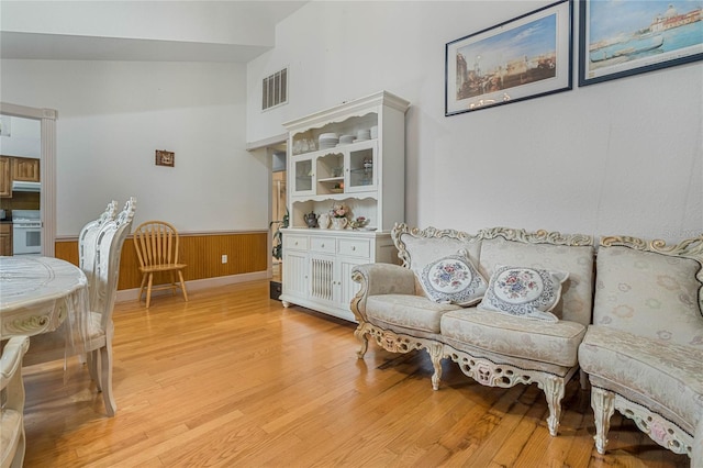 sitting room featuring light hardwood / wood-style floors, lofted ceiling, and wood walls