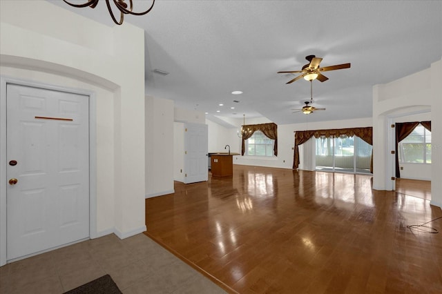 foyer entrance with sink, a textured ceiling, wood-type flooring, and ceiling fan with notable chandelier