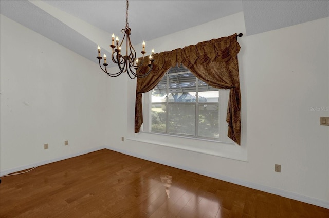 unfurnished dining area featuring an inviting chandelier, a textured ceiling, hardwood / wood-style flooring, and vaulted ceiling