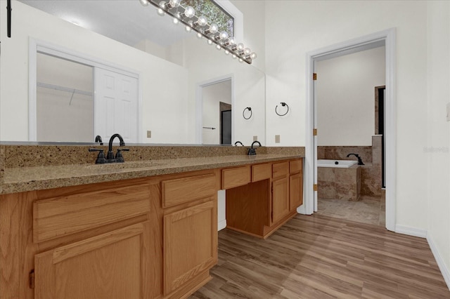 bathroom with vanity, a relaxing tiled tub, and hardwood / wood-style floors