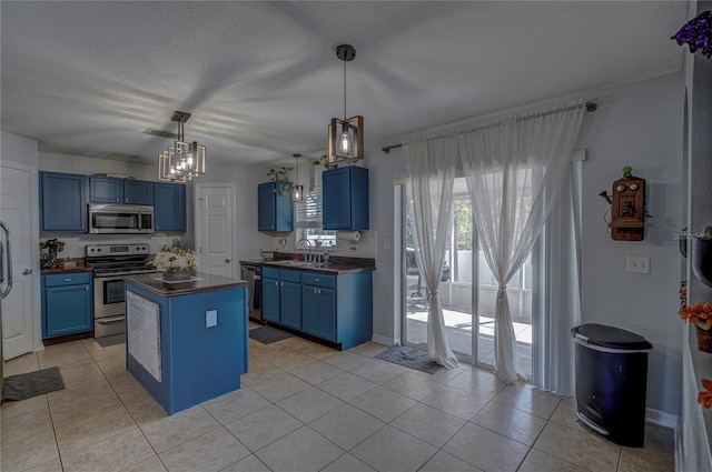 kitchen featuring appliances with stainless steel finishes, light tile patterned floors, hanging light fixtures, sink, and blue cabinets