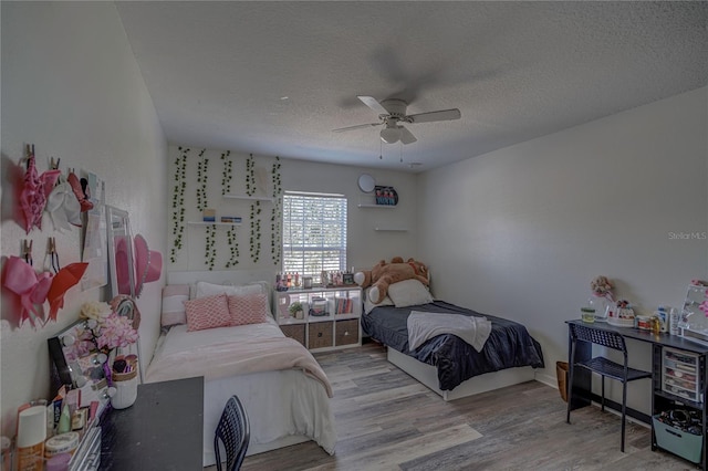 bedroom with a textured ceiling, ceiling fan, and light hardwood / wood-style flooring