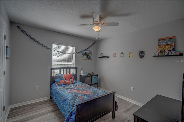 bedroom with a textured ceiling, light wood-type flooring, and ceiling fan