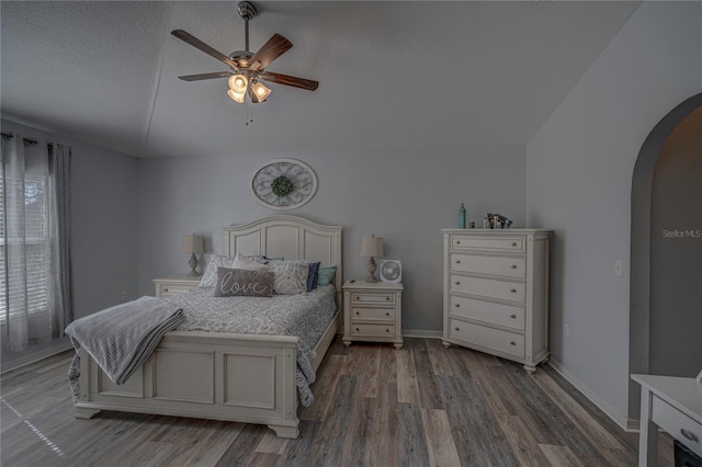 bedroom featuring dark hardwood / wood-style flooring, lofted ceiling, a textured ceiling, and ceiling fan