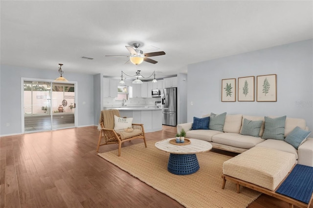 living room with baseboards, a ceiling fan, visible vents, and light wood-style floors