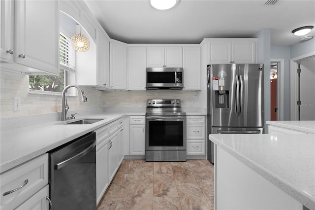 kitchen with white cabinets, decorative backsplash, hanging light fixtures, stainless steel appliances, and a sink