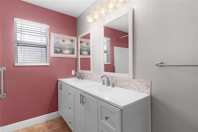 full bathroom featuring a sink, baseboards, and double vanity