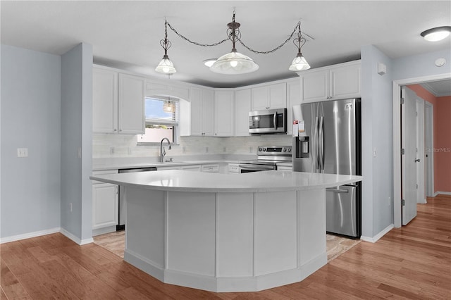 kitchen with stainless steel appliances, a kitchen island, light countertops, and white cabinetry