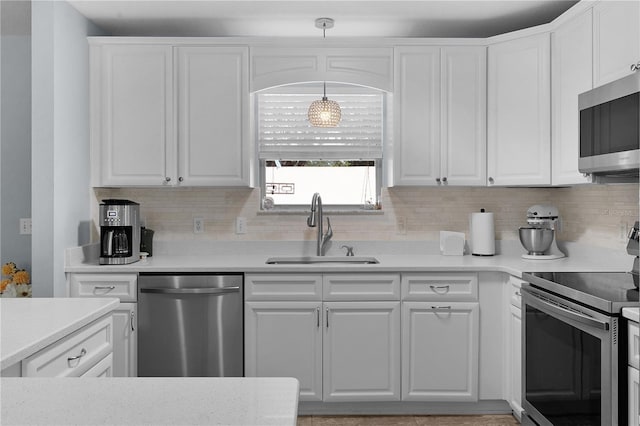 kitchen with hanging light fixtures, white cabinetry, appliances with stainless steel finishes, and a sink