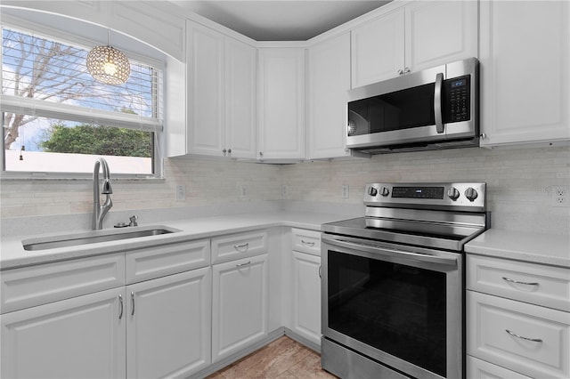 kitchen with stainless steel appliances, light countertops, a sink, and white cabinetry