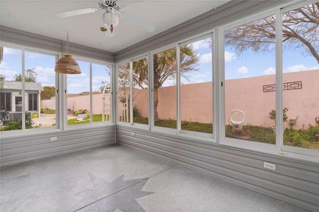 unfurnished sunroom featuring a ceiling fan and a wealth of natural light