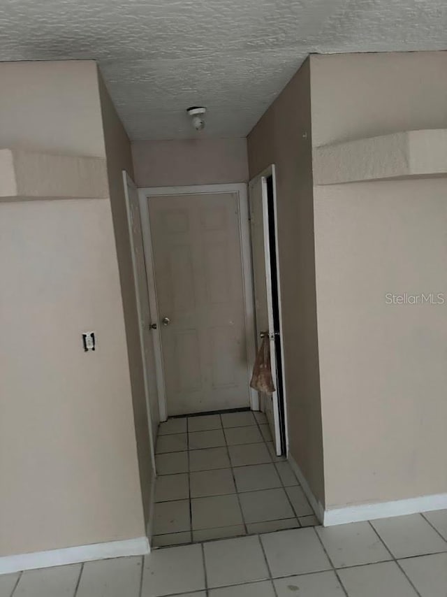 corridor with light tile patterned floors and a textured ceiling